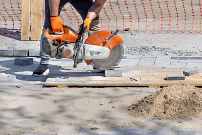 A worker cuts paving blocks at the workplace using a cutting saw and a diamond blade.