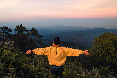 Rear view of man standing by tree against sky during sunset