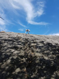 Low angle view of boy climbing on rock against sky