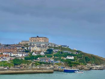 Buildings by sea against sky