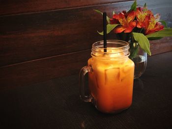 Close-up of orange rose in jar on table