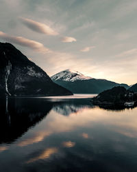 Scenic view of lake by snowcapped mountains against sky