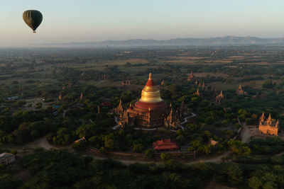 View of hot air balloons flying over bagan pagodas during sunrise against sky