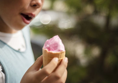 Pink ice cream in a waffle cup in children's hands.