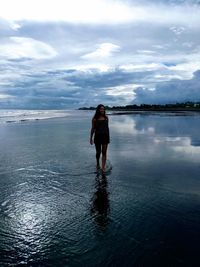 Full length of woman standing on sea against sky