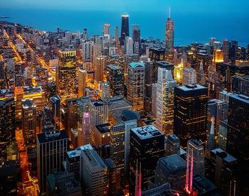 Aerial view of illuminated buildings in city against sky