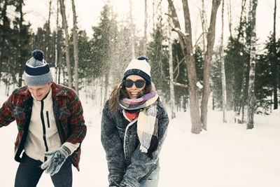 Happy friends playing on snow covered landscape