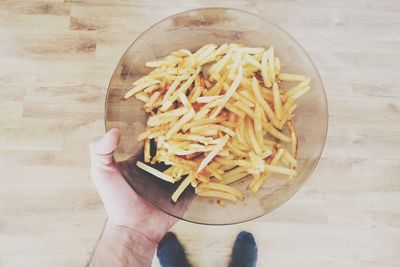 Cropped image of man holding french fries in bowl