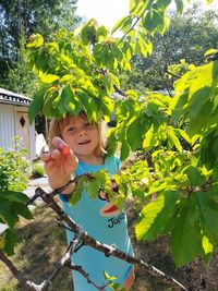 Portrait of girl standing by plants at yard