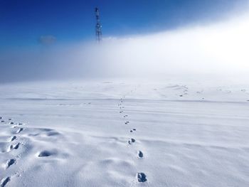 Footprints in the snow leading to a tower in the distance