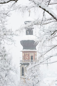 Snow covered house and trees against sky