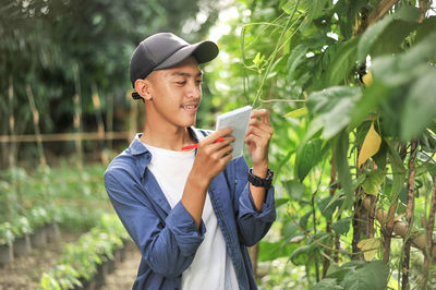 Portrait of smiling young asian farmer man checking quality with small notebook. happy young asian farmer at the garden
