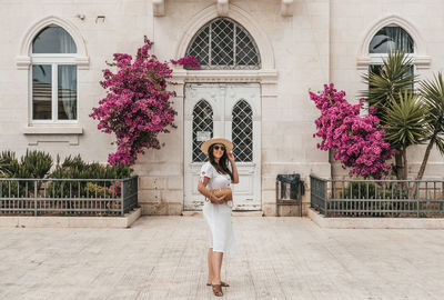 Woman in white dress in front of beautiful building with bougainvillea flowers in trogir, croatia