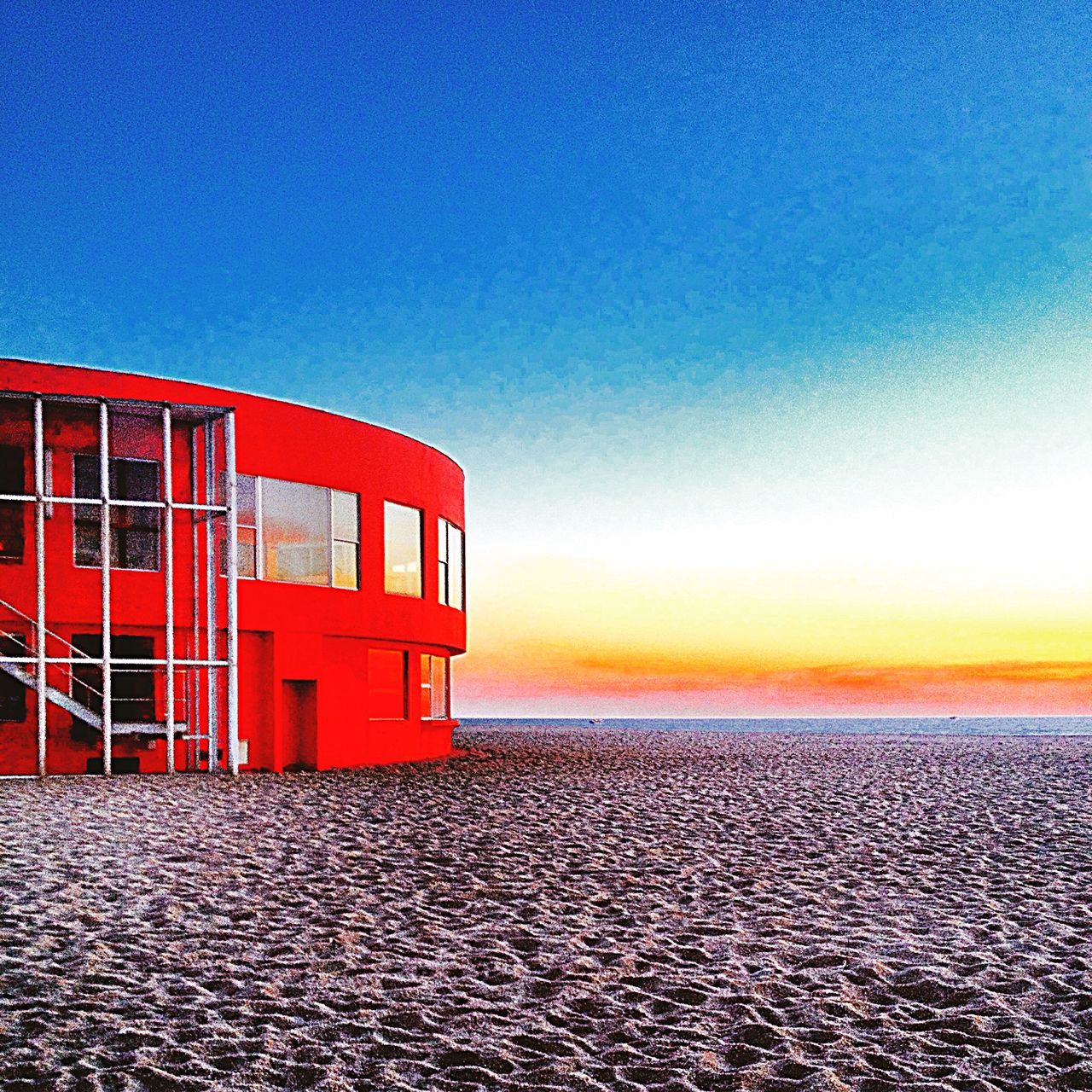 sea, horizon over water, water, clear sky, copy space, sunset, red, built structure, architecture, orange color, building exterior, blue, beach, tranquil scene, tranquility, sky, scenics, outdoors, waterfront, no people