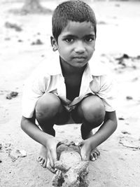 Full length portrait of boy crouching with sand animal at beach