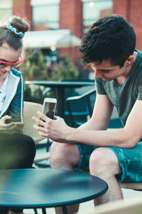 Young man using mobile phone while sitting on laptop