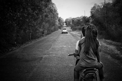 Rear view of girl riding motorcycle on road
