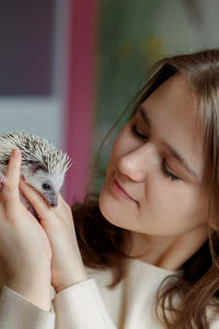 Girl holds cute hedgehog in her hands. portrait of pretty curious muzzle of animal. favorite pets. 