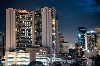 Illuminated buildings in city against sky at dusk