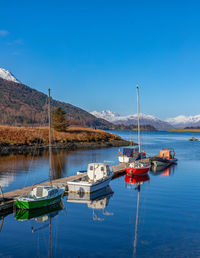 Sailboats moored on sea against blue sky