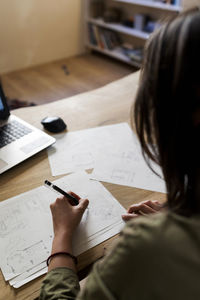 Female design professional making drawing on paper at desk in workshop