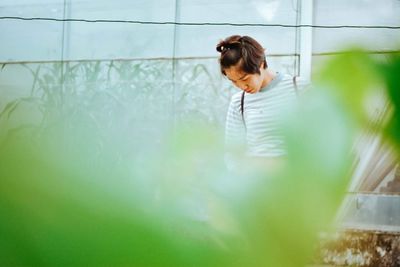 Woman looking down standing by wall