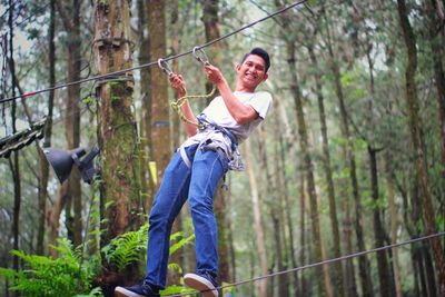 Full length of man holding rope in forest