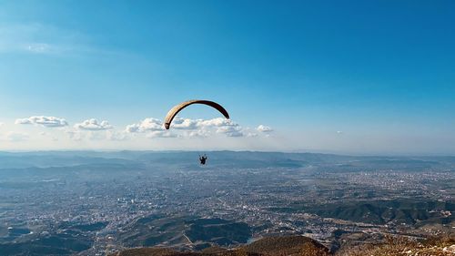 People paragliding over tirana cityscape against sky