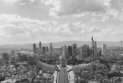 Portrait of man with arms outstretched against cityscape