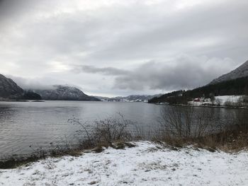 Scenic view of lake by snowcapped mountains against sky