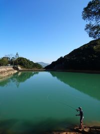 High angle view of man fishing in lake against mountain