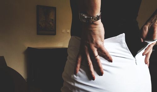 Midsection of woman removing white skirt at home