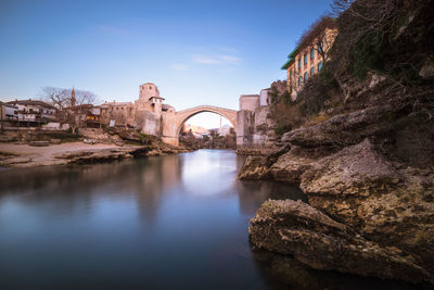 Arch bridge over river against blue sky