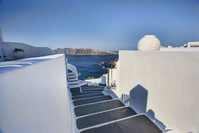 Steps amidst white wall against clear blue sky