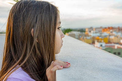 Side view of girl looking away while standing at building terrace