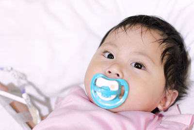 Close-up portrait of cute baby girl lying on bed