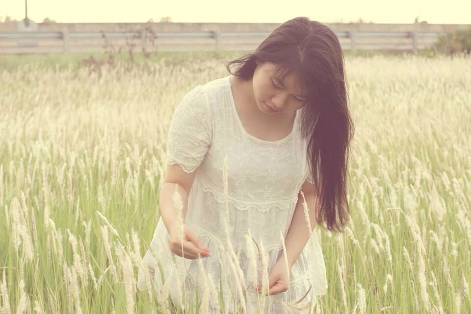 grass, field, person, young adult, lifestyles, young women, grassy, casual clothing, leisure activity, standing, portrait, looking at camera, three quarter length, long hair, front view, smiling, plant