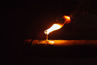 Close-up of lit candle in the dark