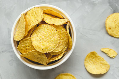 Tortilla corn chips in bowl on a gray background