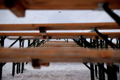 Close-up of wooden benches on snow covered field