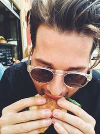 Close-up of a young man eating sandwich