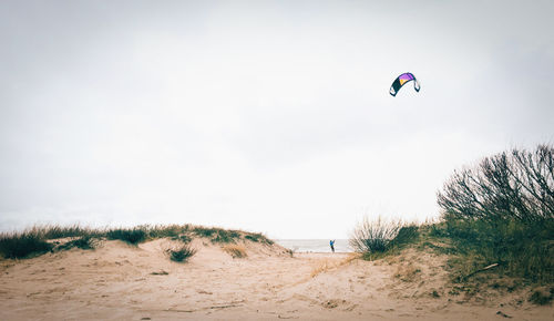 Person kitesurfing on beach against sky