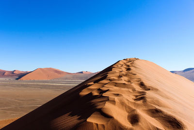 Scenic view of desert against clear blue sky