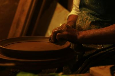 Cropped hands of woman making clay plate