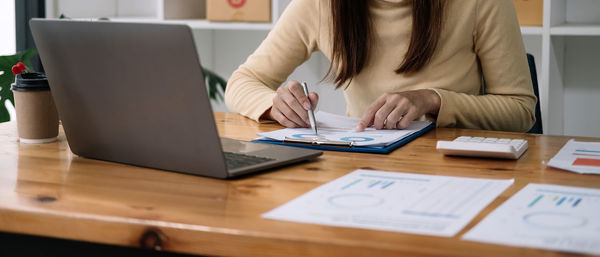 Midsection of businesswoman using laptop at office