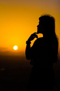 Silhouette woman standing against sky during sunset