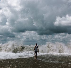 Rear view of teenage boy walking on shore at beach