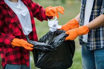 Midsection of man and woman collecting garbage at park