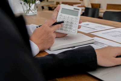 Midsection of man using smart phone on table