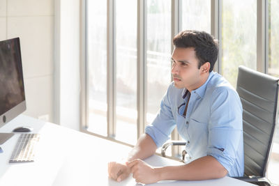 Young man looking down while sitting on table